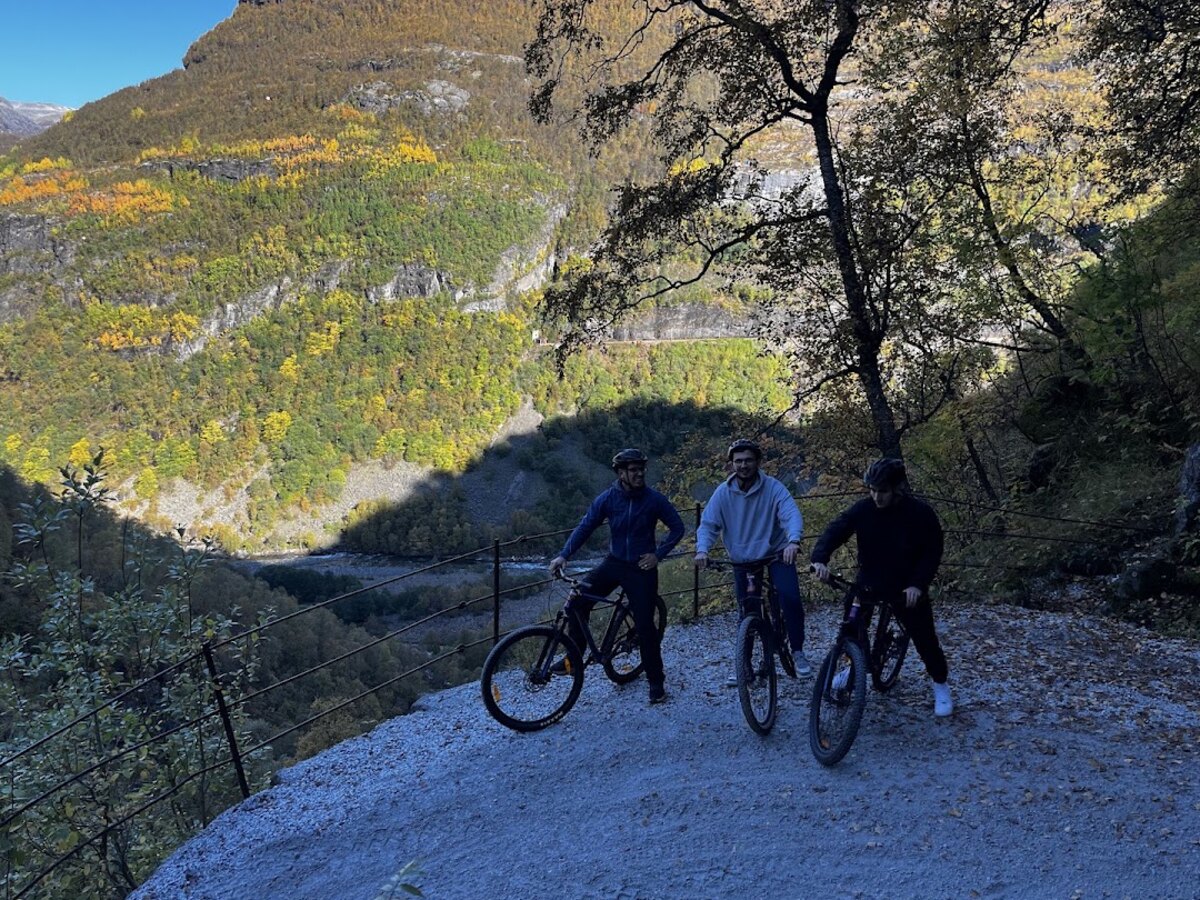 Three cyclists on the gravel mountain switchbacks of Rallarvegen above Flåm valley