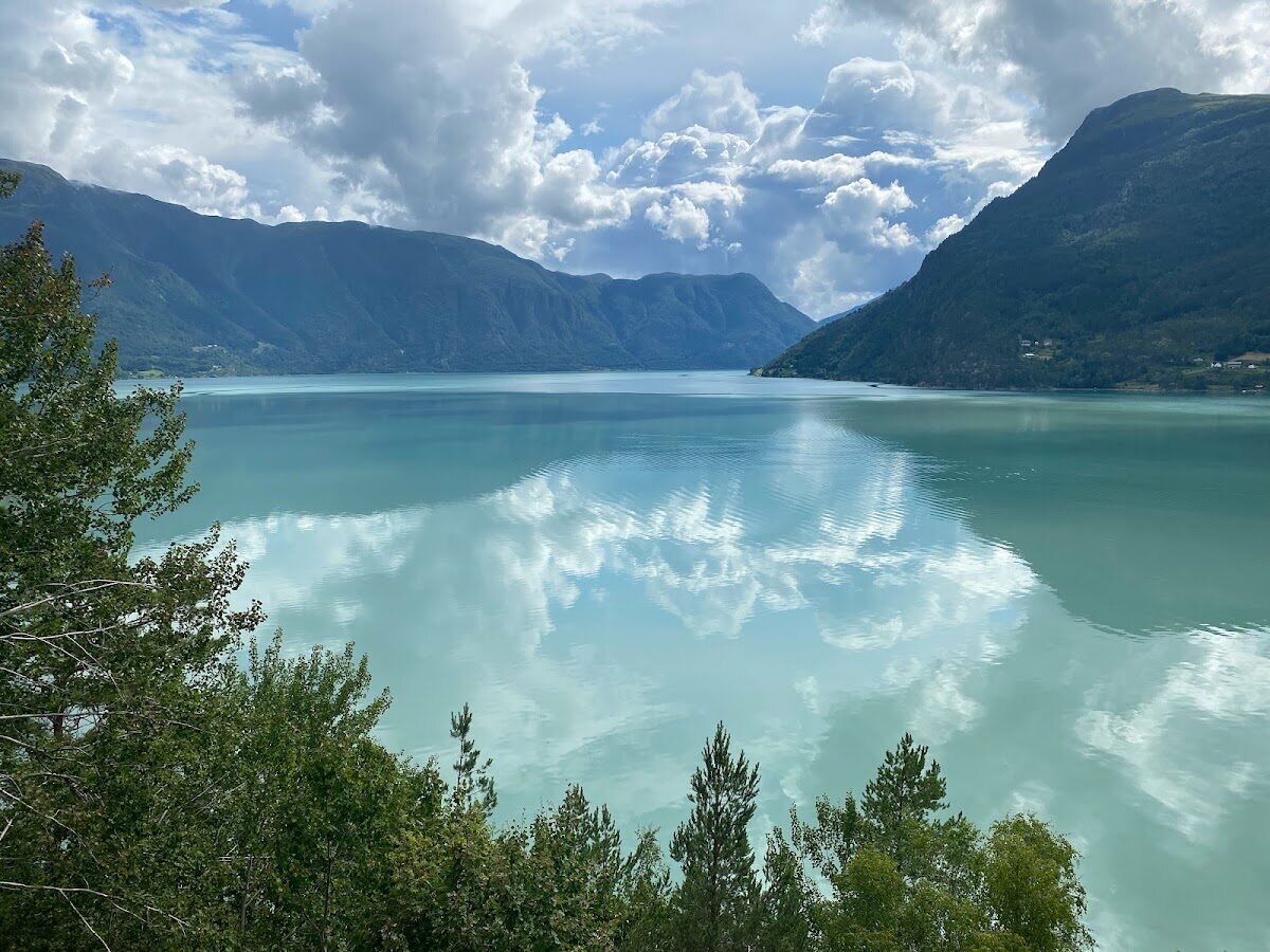 Mirror-still turquoise glacial lake reflecting the clouds and mountains in Western Norway