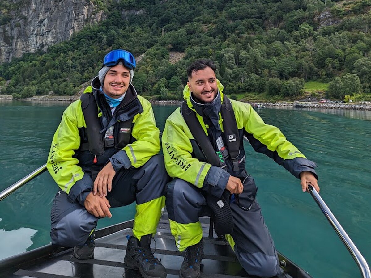 Two travellers on the bow of a RIB boat on emerald fjord waters in Norway